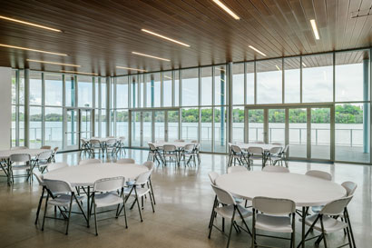 Lakeshore 4 seasons building set up with round tables covered in white table clothes with the beautiful river in the back ground which can be seen through all of the windows