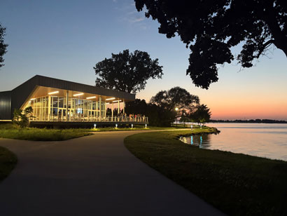 A beautiful picture of the Lakeshore 4 seasons building in the evening with all of the lights on and the sun setting in the background