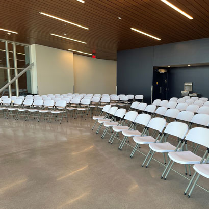 The inside of the Lakeshore 4 seasons building set up with white chairs on each side of the room with an open row down the middle