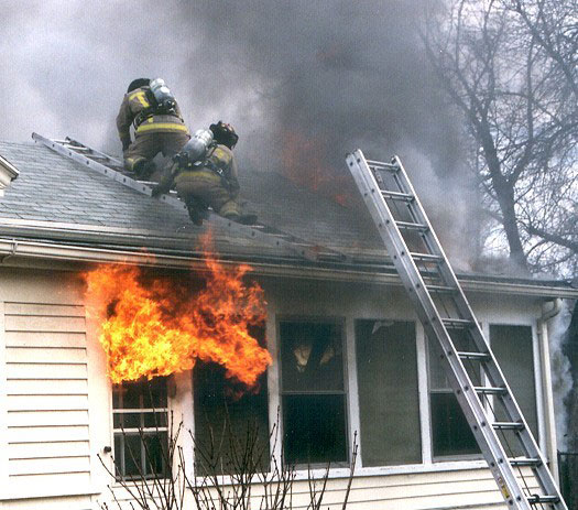 Firefighters on a roof with fire in the window