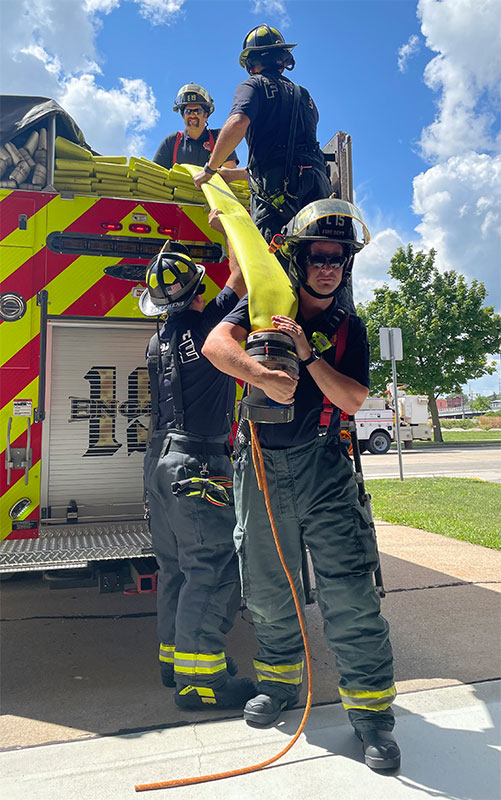 Photo of firefighters removing a hose from a fire truck