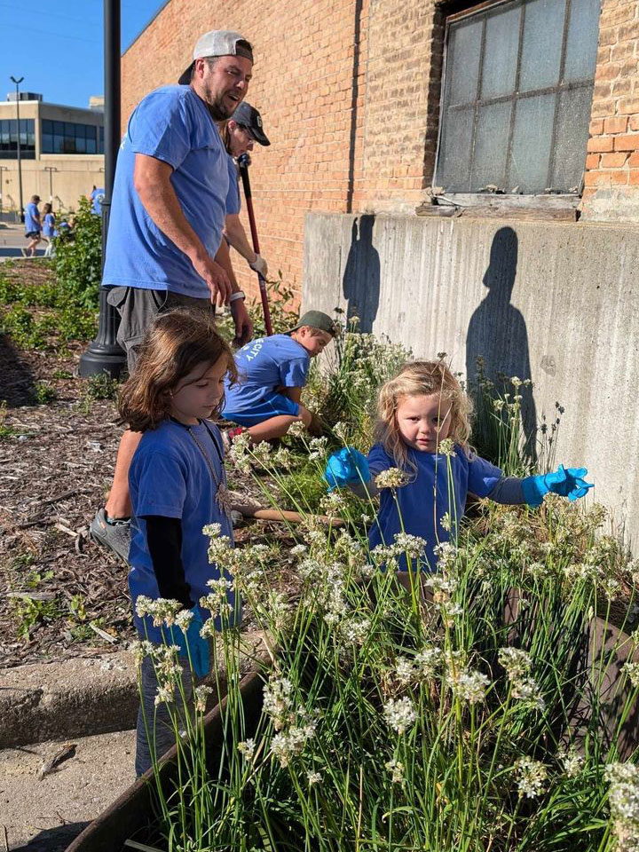 A group of volunteers work in downtown Oshkosh cleaning up some of the landscape beds